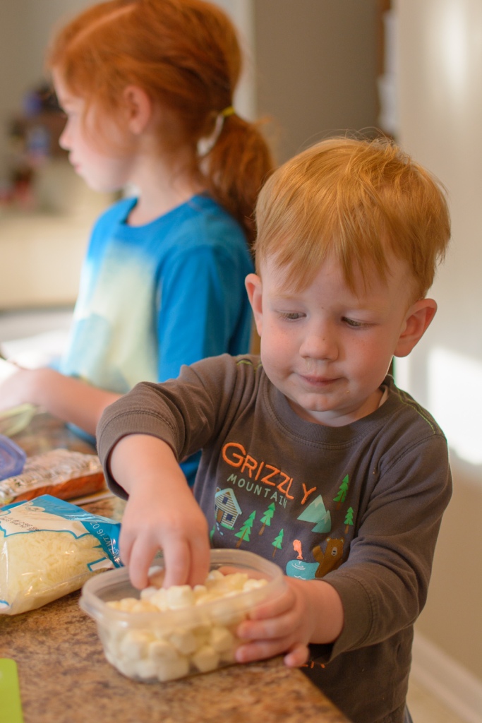 Toddler teaching into mozerella cheese container